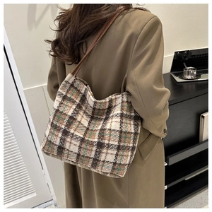 Detail of vintage plaid tweed tote bag with leather straps and textured fabric finish