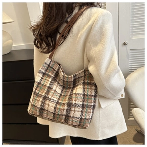 Detail of vintage plaid canvas tote bag with brown leather straps on model's shoulder