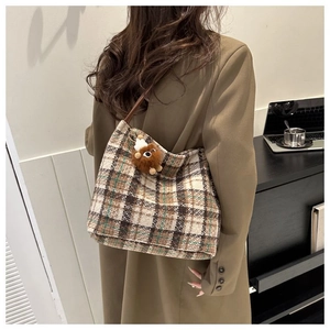 Close-up of retro plaid canvas tote bag with a cute brown plush pendant detail