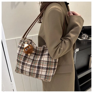 Detail of vintage plaid tweed tote bag featuring brown leather straps and plush charm