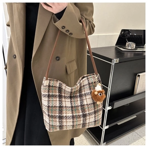 Detail of vintage plaid canvas hobo tote with leather strap and plush charm