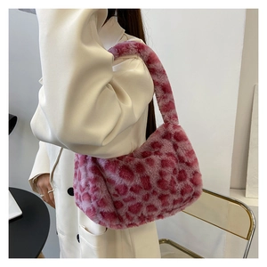 Pink leopard print plush shoulder bag shown being worn over a stylish white jacket