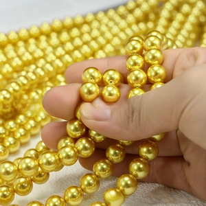 Macro shot of metallic golden imitation pearls for DIY jewelry making and necklaces