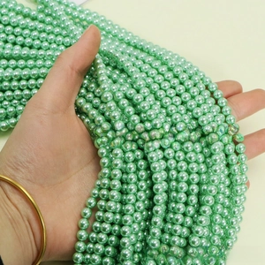 Detailed close-up of light green round imitation pearls for DIY jewelry making
