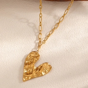 Detail of 18k gold plated heart necklace with unique textured lava finish on oval link chain