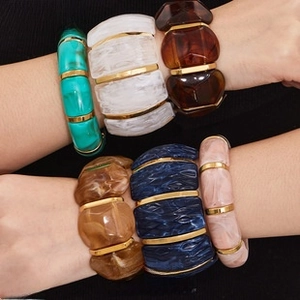 Dettaglio di bracciali in resina colorata marmorizzata con accenti in metallo dorato