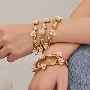 Dettagli di eleganti bracciali floreali in smalto con finitura oro e accenti di cristallo