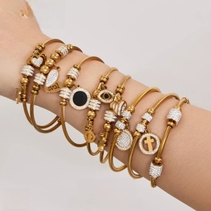 Braccialetti dorati a strati con ciondoli a cuore, croce e occhio con strass bianchi