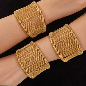 Vista dettagliata di bracciali a polsino in filo dorato multistrato indossati dal modello
