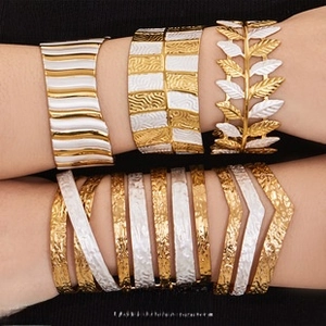 Dettaglio di bracciali a strati in oro e argento con rilievo a foglia e motivi a onde