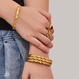 Primo piano di un anello a cuore d'oro e un bracciale a treccia indossati al polso