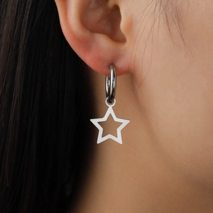Minimalist stainless steel hoop earrings with hollow star pendants worn by a model