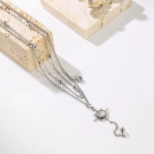 Three-layer silver starburst sun pendant necklace on textured beige stone props