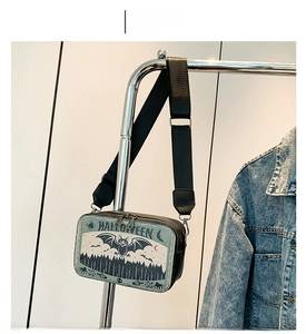 Detail of Halloween crossbody bag with bat print and adjustable strap on metal hanger