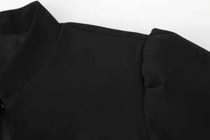 Detail von schwarzen Puffärmeln und Stehkragen an einem schmalen Damen-Oberteil