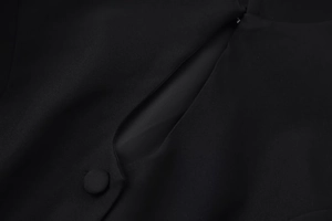 Detailansicht eines schwarzen schmal geschnittenen Oberteils mit stoffbezogenem Knopf und Cut-Outs