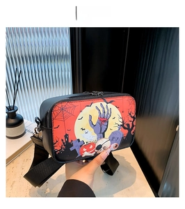 Close-up of a small square crossbody bag with Halloween themed zombie hand and pumpkin prints