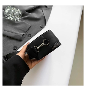 Close-up of black crossbody bag side with silver D-ring buckle and zipper detail