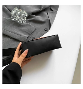 Detail view of the sleek rectangular base and matte black leather of the crossbody bag
