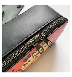 Macro shot of double metal zippers and anime character printing on the shoulder bag