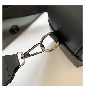 Detail of metal lobster clasp and D-ring on a black leather crossbody bag shoulder strap