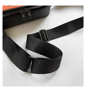 Detail of adjustable nylon strap and silver-tone metal buckle on black crossbody bag