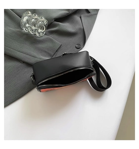 Close-up of black leather crossbody bag with orange art print and silver metal zipper detail