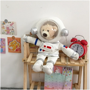 Close-up of cute astronaut bear plush bag with metallic chain on a wooden shelf