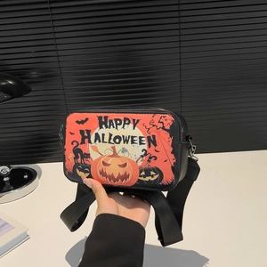 Halloween crossbody bag with orange pumpkin prints and adjustable black strap on white desk
