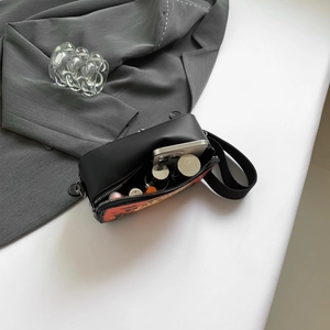 Chic black crossbody bag with orange abstract print showing spacious inner capacity