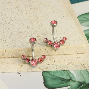 Detailed shot of curved stainless steel navel rings with pink crystals on stone decor