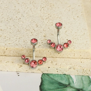 Detail of pink zircon navel rings with stainless steel curved bars on a stone display