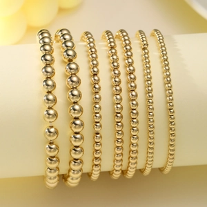 Detail of 7-piece set gold bead stretch bracelets with sizes ranging from 3mm to 8mm