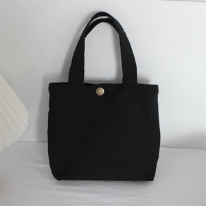 Detail of black canvas tote bag showing the sturdy fabric and vintage bronze snap button