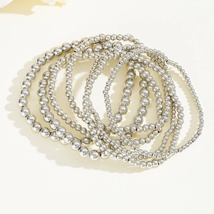 Detail shot of a 7-piece set of polished silver beaded stretch bracelets on a white base