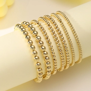 Set of 6 gold beaded elastic bracelets in various sizes on a display stand