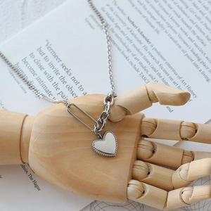 Silver heart pendant necklace with unique safety pin chain links held by wooden model hand