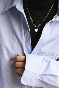 Close-up of silver heart pendant with beaded edge and asymmetrical safety pin chain