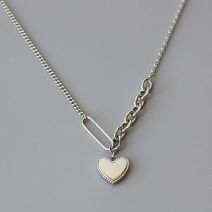Silver asymmetrical chain necklace with heart pendant and textured bead edge detail