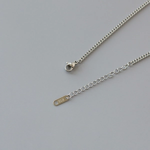 Macro shot of silver titanium steel lobster clasp and K18 engraved tag for necklace