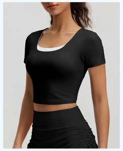 Détail du haut de yoga noir à manches courtes avec col superposé blanc et coupe ajustée