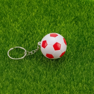 Gros plan du mini porte-clés football rouge et blanc sur un fond de pelouse verte