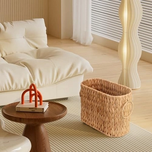 Close-up of woven rattan storage basket with round handles in a modern living room