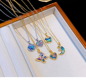 Détail de colliers papillon, cœur et lune avec pendentifs en nacre aux reflets irisés