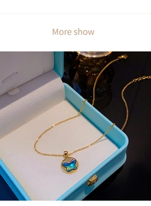 Gros plan sur collier papillon doré avec pendentif nacre irisée dans son coffret