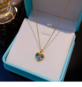 Détail du collier cœur avec incrustation de coquillage irisé et pierre rose sur boîte bleue