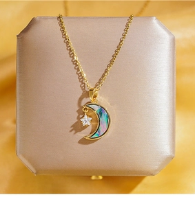 Détail du pendentif lune et étoile dorée avec nacre irisée sur un écrin à bijoux en soie