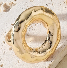 Close-up of golden irregular open ring with hammered texture on travertine stone