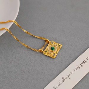 Detail of vintage square gold necklace with green gemstone and zircon embellishments