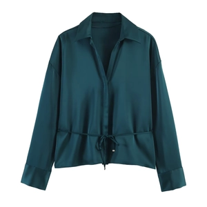 Detail of dark green satin blouse showing smooth glossy texture and tie waist design